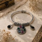 Antique Petals Anklet featuring an oxidized silver finish with a colorful floral charm and black stone drop charms, handcrafted in a vintage-inspired design for traditional and fusion wear.