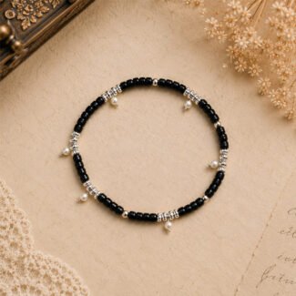 Handcrafted Moon Drop Anklet featuring black glass beads, silver-tone spacer beads, and delicate pearl drop charms, displayed on a soft vintage beige background.