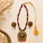 Srida Mandala Necklace Set with antique gold finish, handcrafted red and green beaded necklace, ornate mandala pendant, and matching earrings for festive and traditional wear.