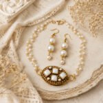 Srida Moonlit Pearl Choker Set with antique gold-tone finish, ivory pearl details, lobster clasp lock, and matching pearl hook earrings on a light vintage background.