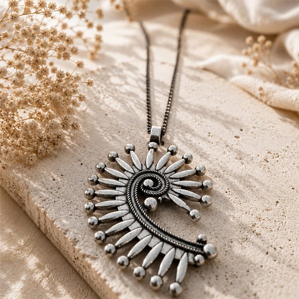 Tribal-Sun-Spiral-Pendant Oxidised silver Tribal Sun Spiral Pendant with an intricate spiral design and radiating teardrop-shaped details.