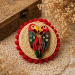 Handmade jute finger ring featuring two colorful wooden birds facing each other in a heart-like pose, finished with red pom-pom detailing.