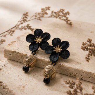 Black clay blossom earrings with textured petals, oxidised detailing, gold-toned floral centres, ribbed round drops, and black bead accents.