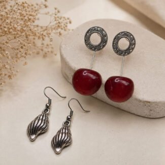 Timeless oxidised combo earrings featuring antique silver-toned filigree earrings with deep red statement beads and textured shell-inspired drop earrings.