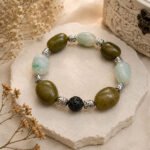 Olive semi-precious stone bracelet with Buddha beads, silver-toned accents, and a dark textured centerpiece arranged in a vintage style.