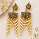 Srida antique oxidised gold pearl drop earrings with ornate peacock-inspired detailing and cascading white pearl beads.