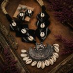 Black Weave Cowrie Oxidised Necklace Set featuring black cloth, natural cowrie shells, an intricate oxidised pendant, and matching statement earrings.