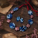 Indigo Folk Charm Necklace Set with blue batik fabric elements, red and white patterned beads, and matching handcrafted earrings.