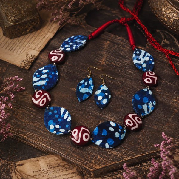 Indigo-Folk-Charm-Necklace-Set Indigo Folk Charm Necklace Set with blue batik fabric elements, red and white patterned beads, and matching handcrafted earrings.