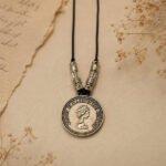 Antique Coin Pendant with Queen Elizabeth II portrait, detailed metal accents, and black cord.