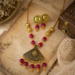 Temple Ganesha Antique Necklace Set with oxidised finish, premium red beads, and a handcrafted Ganesha pendant, displayed in a vintage-inspired arrangement.